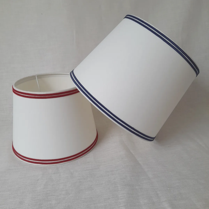 White and blue lampshade shape are in ivory cotton percale edged with Basque red or navy blue double braid.